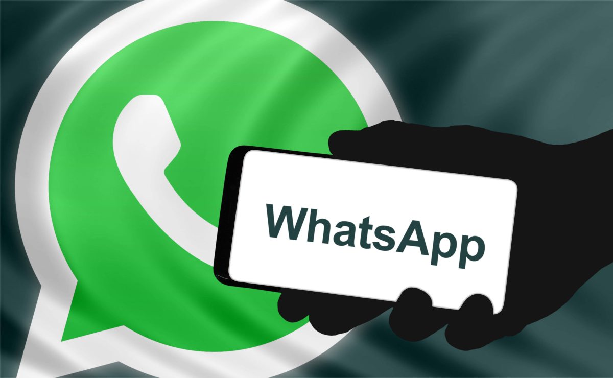 Ein Smartphone mit dem Whatsapp-Schriftzug ist vor einem Whatsapp-Logo zu sehen.