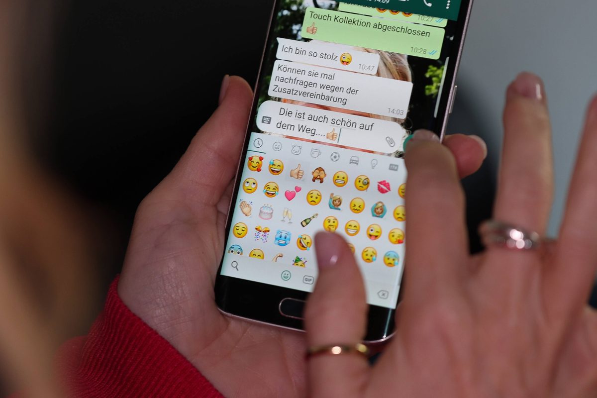 die Hände einer Frau tippen eine Nachricht in den Messenger Whatsapp auf einem Smartphone.