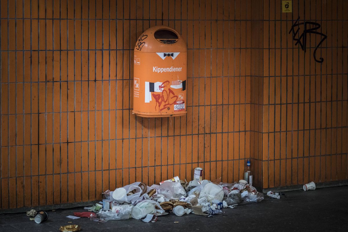 Muell liegt unter einem Muelleimer in Berlin.