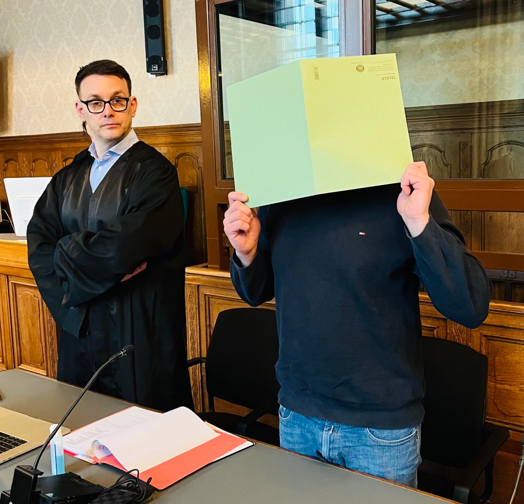 Susar S. neben seinem Verteidiger. Er soll in Berlin mit Drogen im Wert von einer halben Million Euro gedealt haben. Er verdeckt sein Gesicht mit einer hellgrünen Mappe.