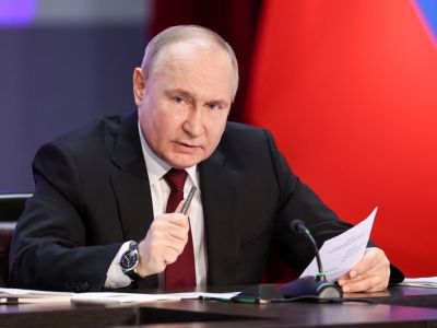 Russland-Präsident Wladimir Putin sitzt an einem Tisch, mit einem Zettel in der linken Hand.