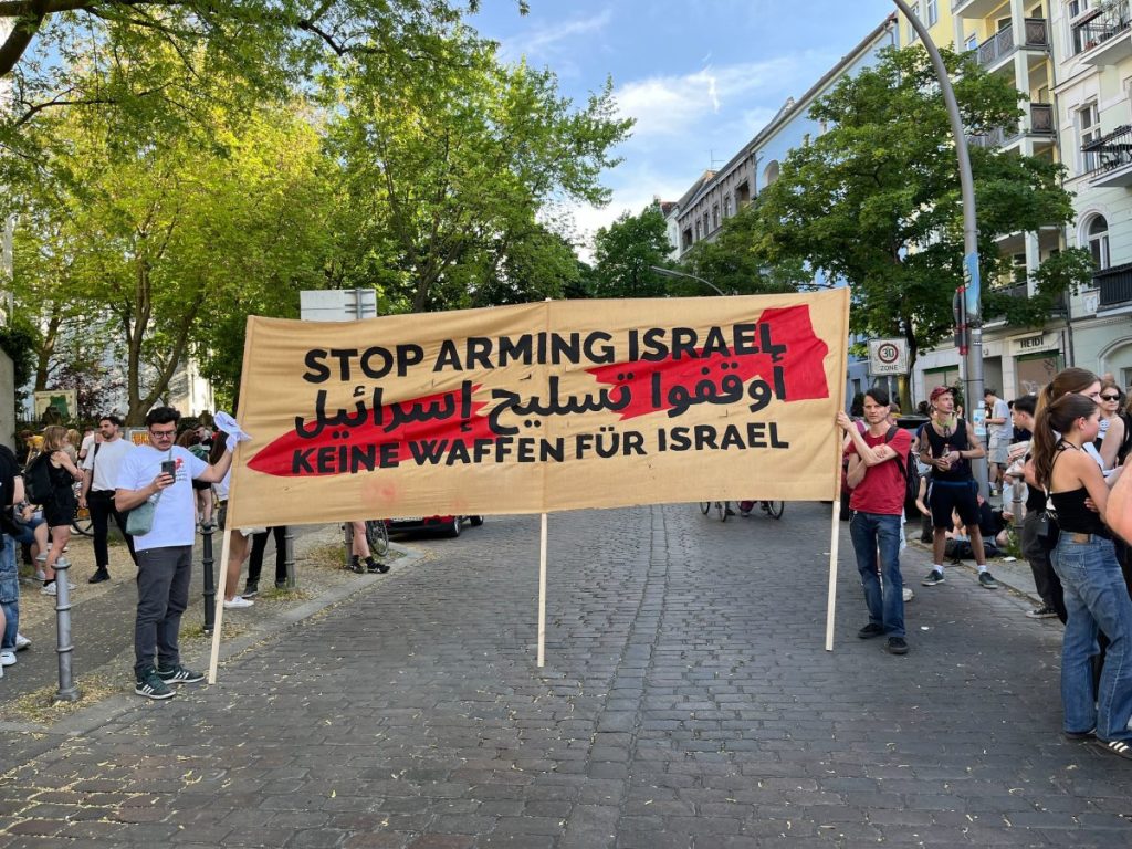 Auf einem Transparent wird in Berlin-Kreuzberg zum Stopp von Waffenlieferungen an Israel aufgerufen.