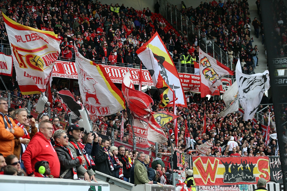 Fans von Union Berlin schwenken im Stadion die Fahnen.