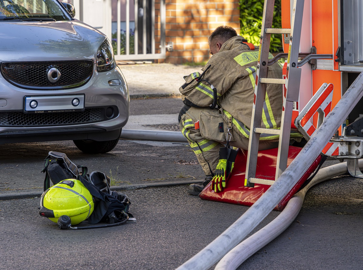 Ein Berliner Feuerwehrmann sitzt neben einem Einsatzfahrzeug.