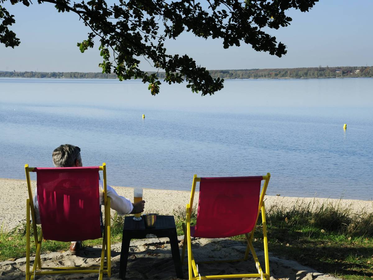 Mann sitzt auf einem Stuhl am See