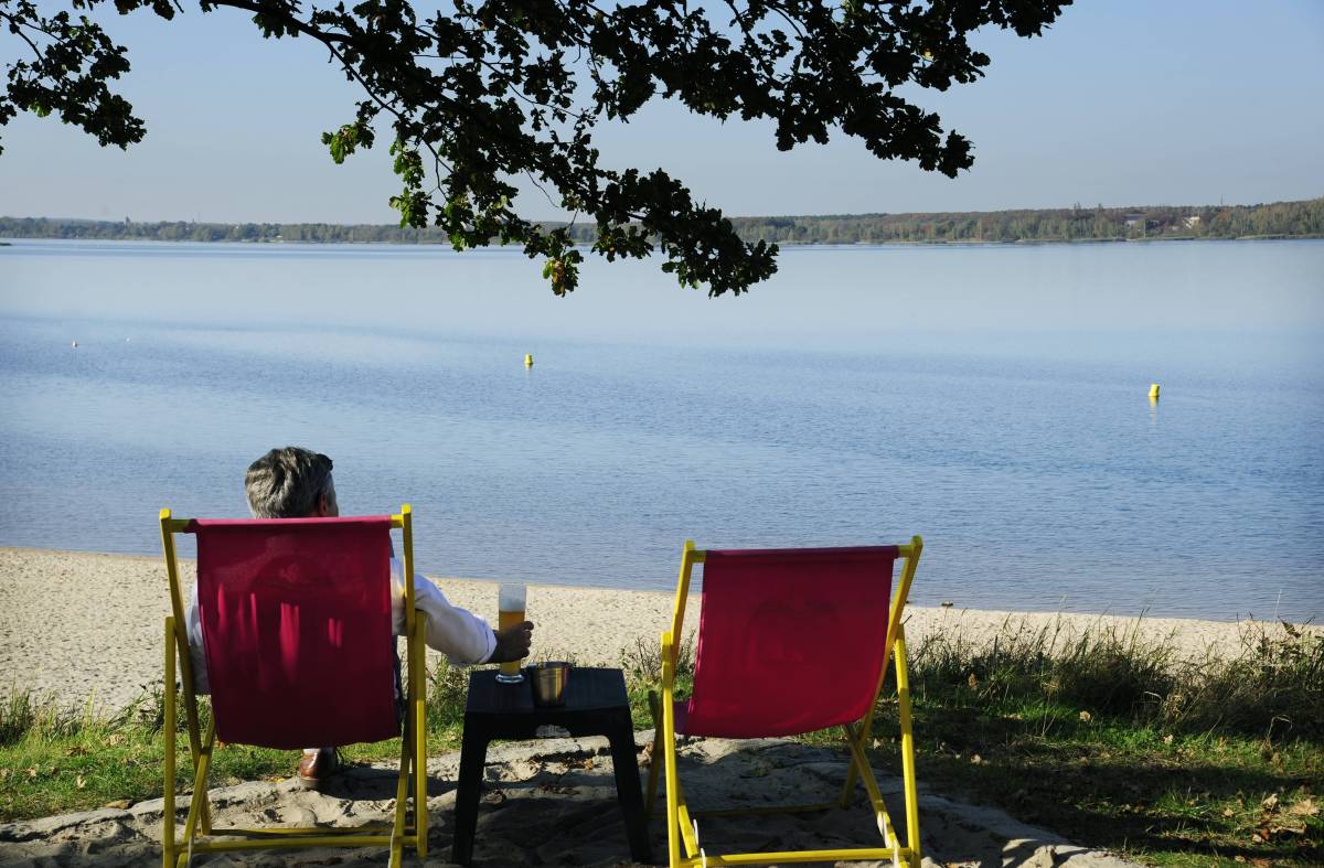Mann sitzt auf einem Stuhl am See